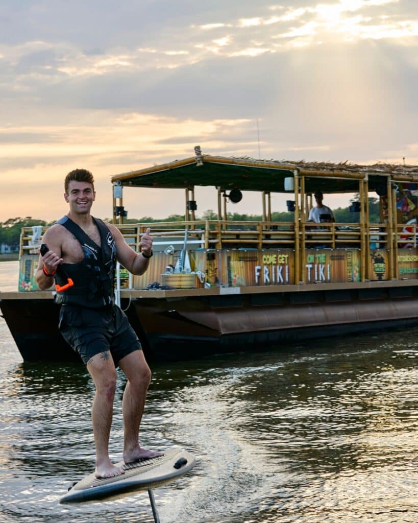 Man riding an electric foil board next to the Friki Tiki during a special adventure cruise in Charleston Harbor.