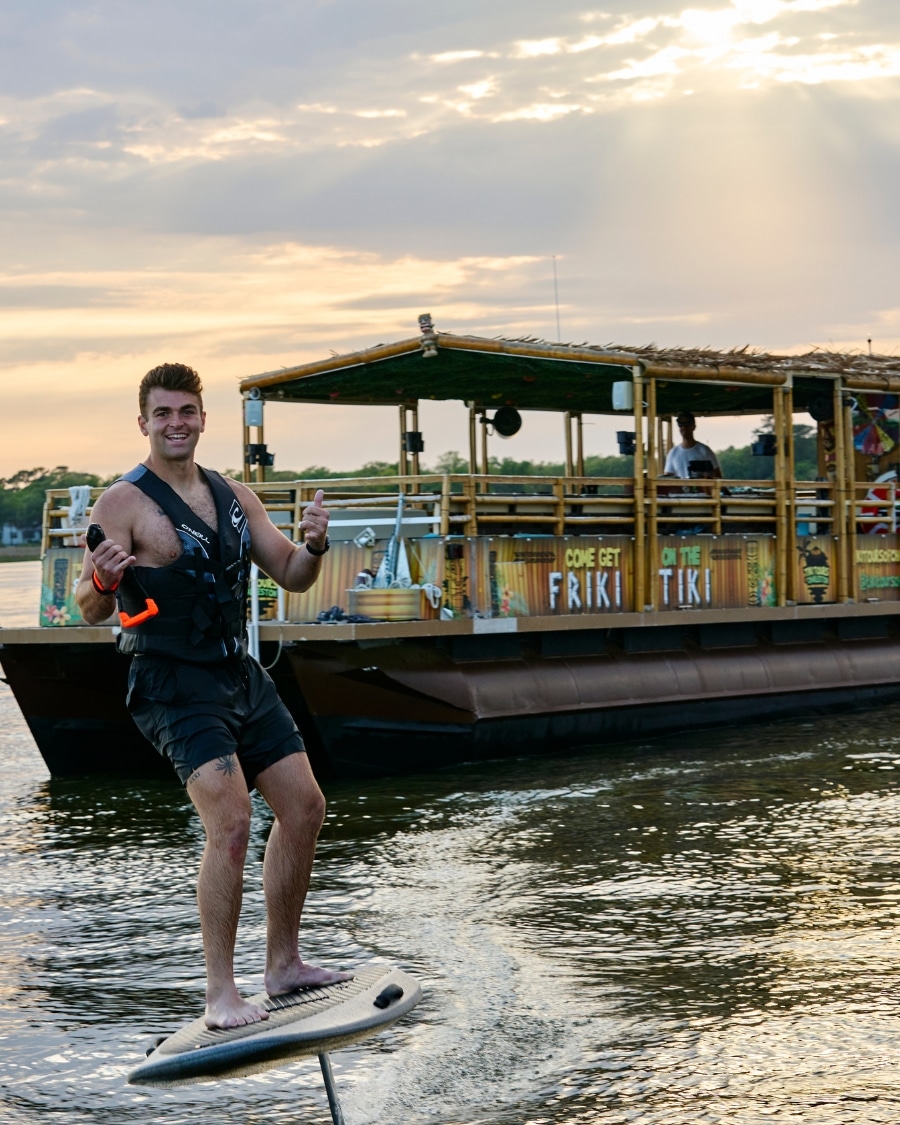 Man riding an electric foil board next to the Friki Tiki during a special adventure cruise in Charleston Harbor.