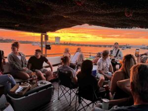 Passengers wearing casual tropical attire and enjoying a drink aboard the Friki Tiki in Charleston.