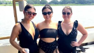 A bride-to-be and her bridesmaids smiling and holding drinks on a private bachelorette party boat in Charleston.