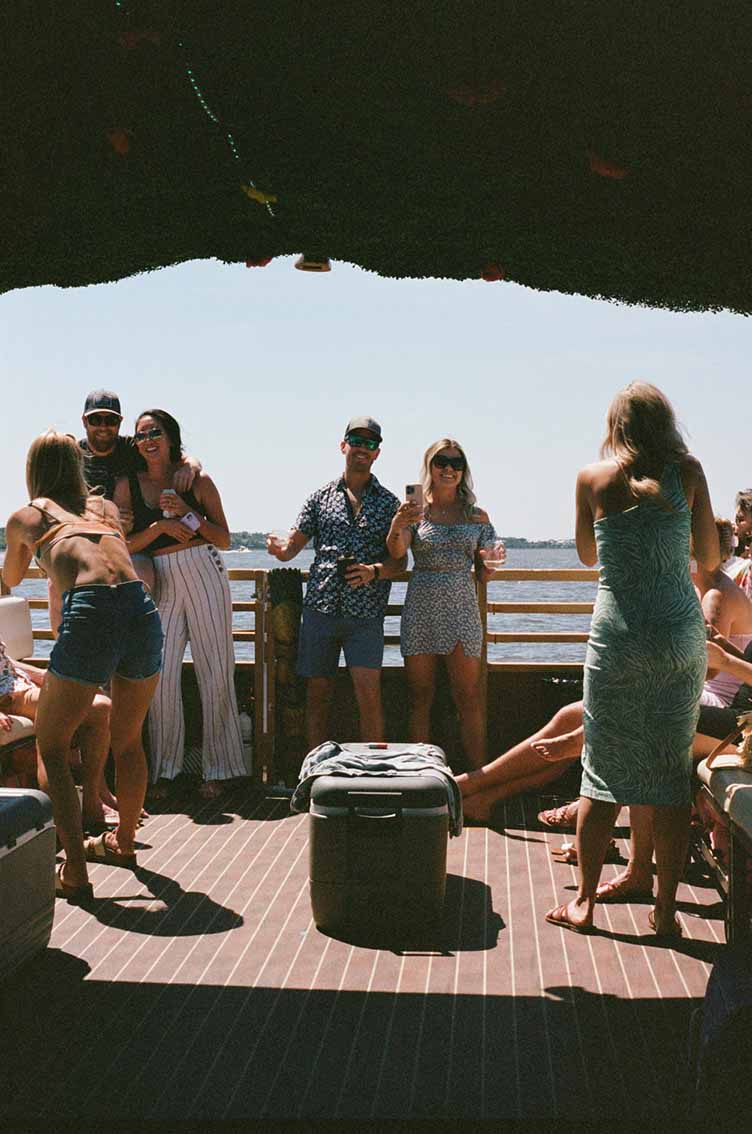 Best Party Boat Charleston SC - Tiki Tours The Friki Tiki party boat by Tiki Tours of Charleston cruising through the harbor with a large group of passengers enjoying drinks and music.