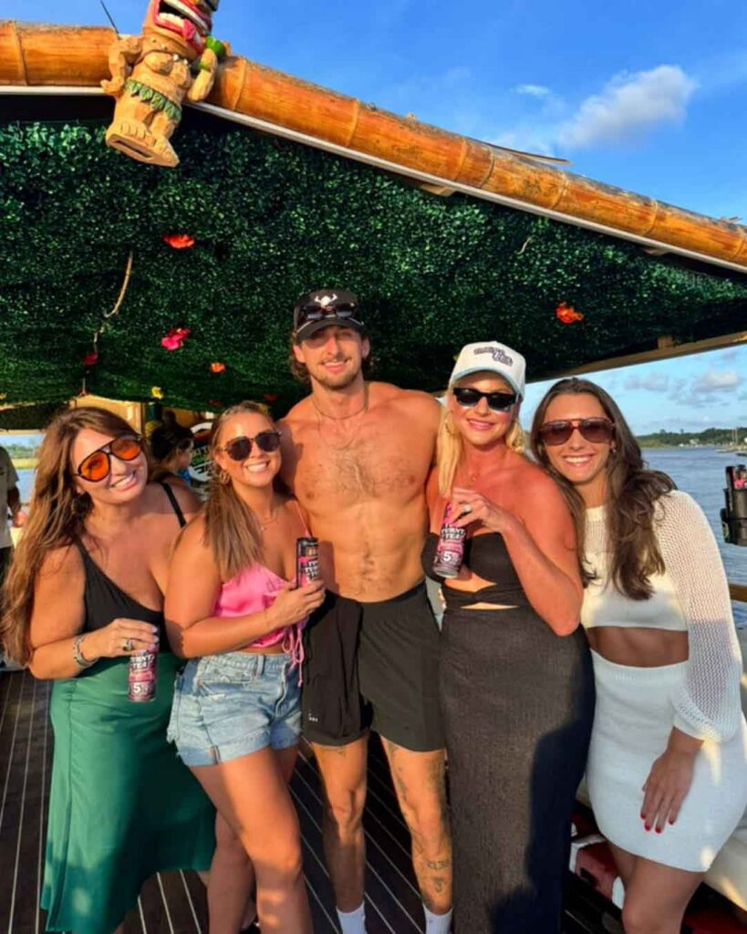 Charleston City Skyline Party Boat Tour A large group of passengers celebrating on the Friki Tiki party boat with the Charleston city skyline visible in the background.