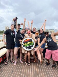 A group of people socialising and enjoying drinks at the bar of the Friki Tiki boat during a Charleston Harbor cruise