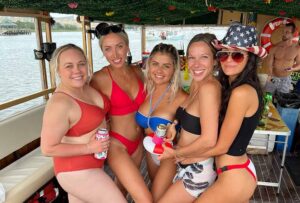 A bachelorette party group celebrating on the Friki Tiki party boat in Charleston Harbor with the Arthur Ravenel Jr. Bridge in the background.