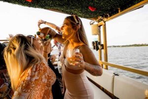 Passengers relaxing in the comfortable lounge seating of the Friki Tiki boat while cruising the Charleston Harbor at sunset.